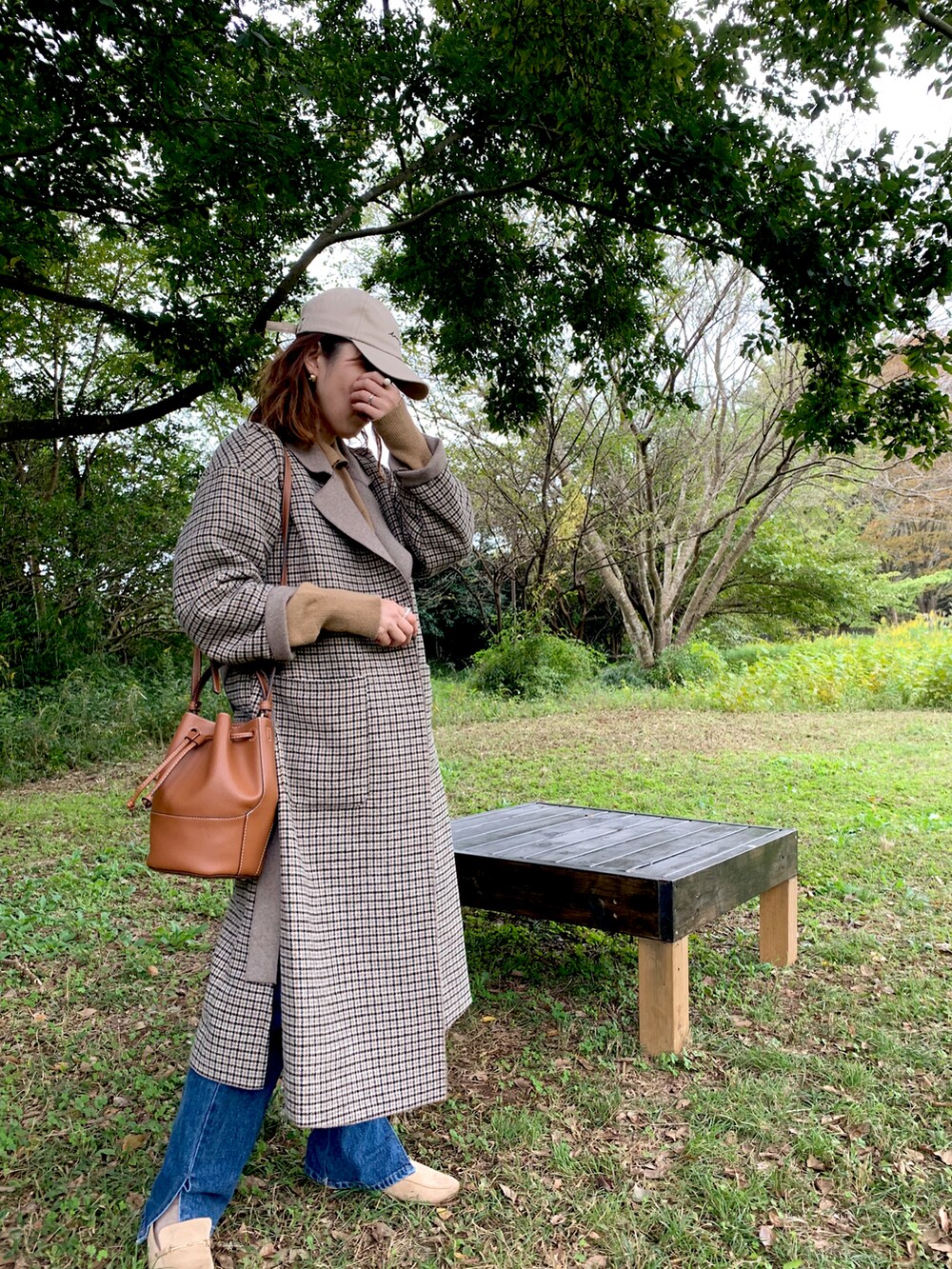 ベージュ系のチェスターコート、ベージュ系のローファー、ブラウン系のショルダーバッグを着用したレディースの秋コーディネートの3枚目の写真