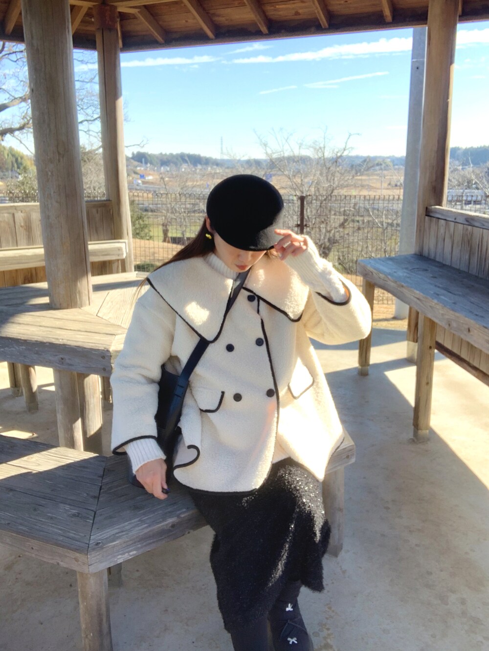 ブラック系のトートバッグ、ブラック系のスカート、ベージュ系のキャスケットを着用したレディースの冬コーディネートの2枚目の写真