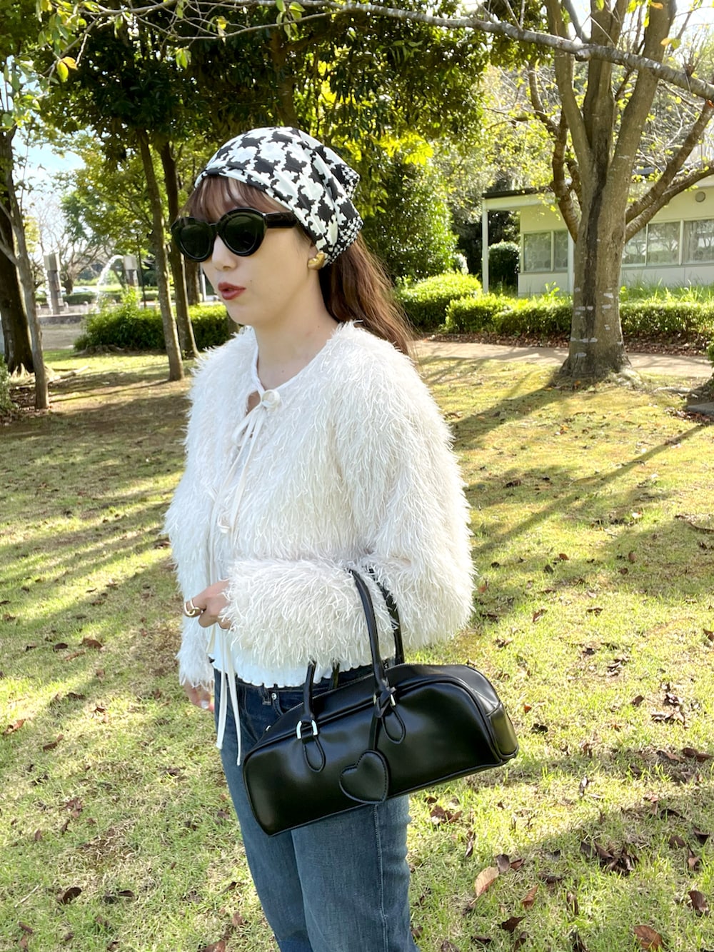 ブラック系のボストンバッグ、ホワイト系のカーディガン/ボレロ、ブルー系のデニムパンツを着用したレディースの秋コーディネートの4枚目の写真