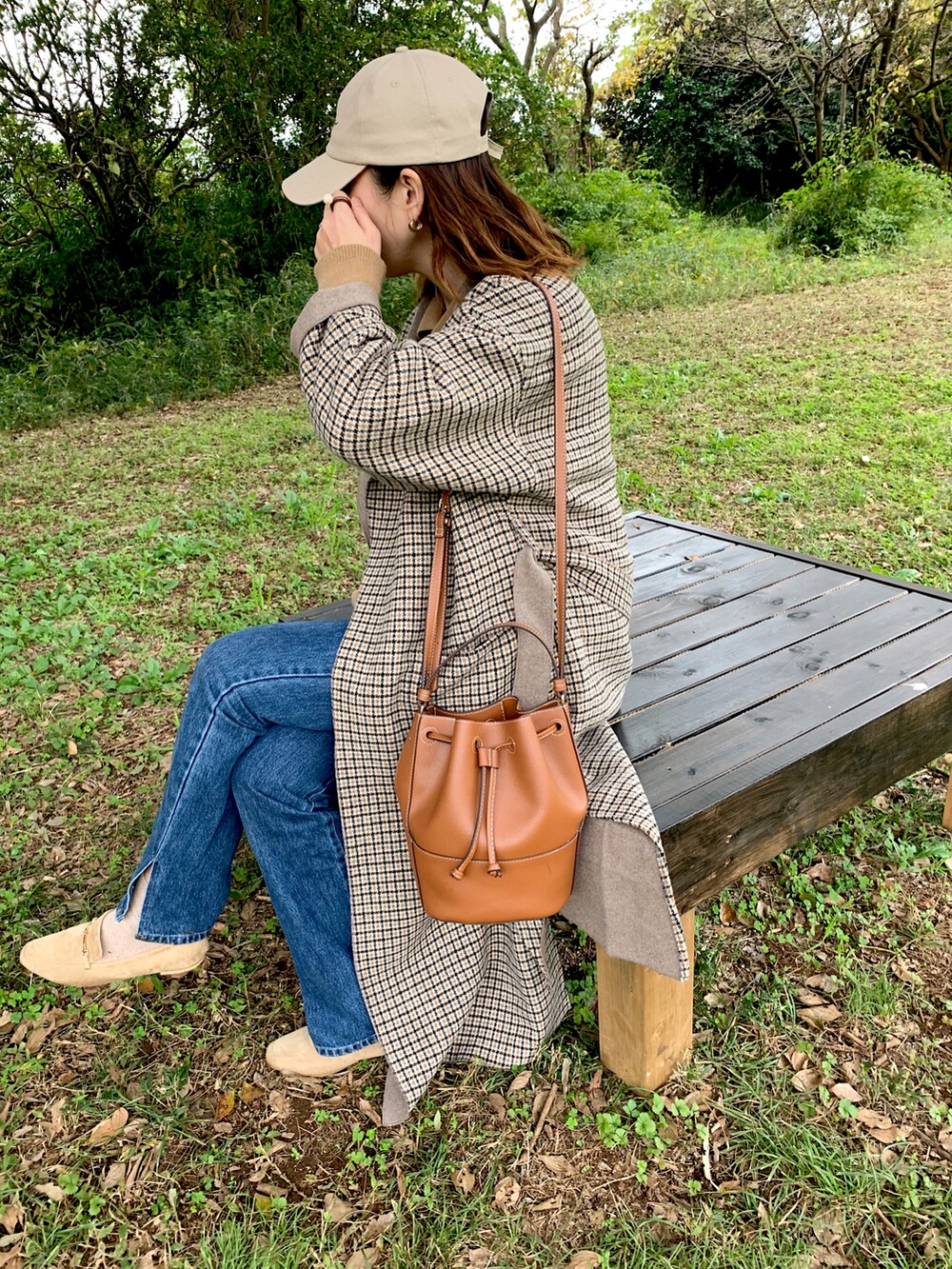 ベージュ系のチェスターコート、ベージュ系のローファー、ブラウン系のショルダーバッグを着用したレディースの秋コーディネートの2枚目の写真