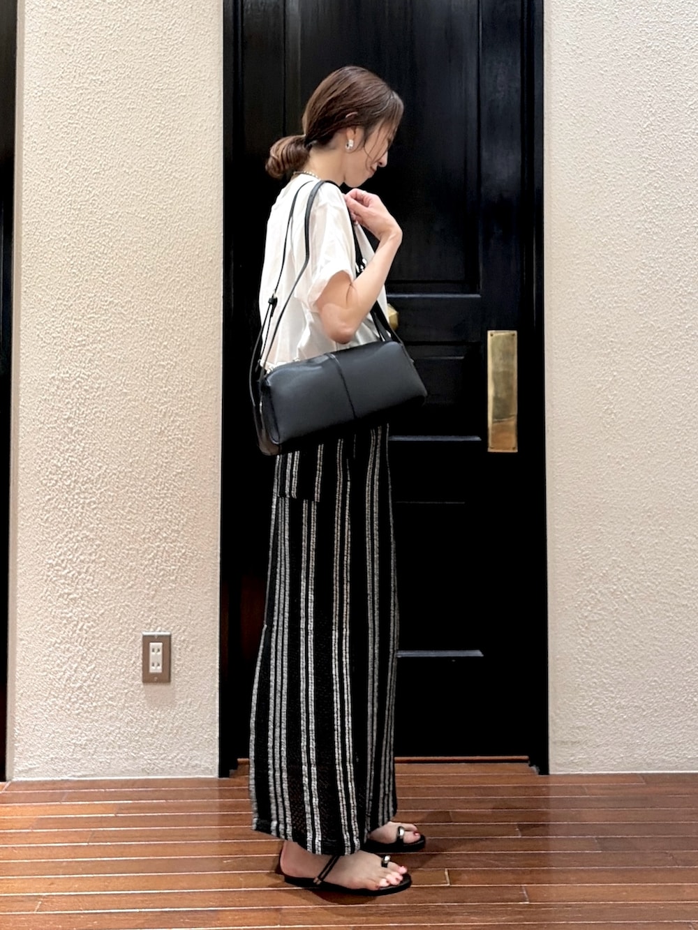 ブラック系のスカート、ホワイト系のTシャツ/カットソー、ブラック系のサンダルを着用したレディースの夏コーディネートの2枚目の写真