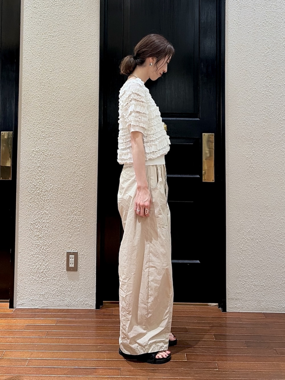 ベージュ系のその他パンツ、ホワイト系のニット/セーター、ブラック系のサンダルを着用したレディースの夏コーディネートの2枚目の写真