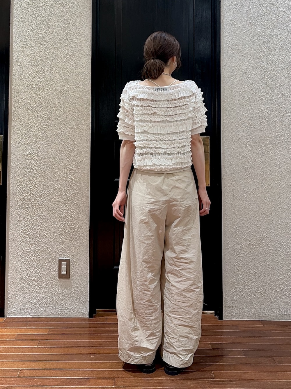 ベージュ系のその他パンツ、ホワイト系のニット/セーター、ブラック系のサンダルを着用したレディースの夏コーディネートの3枚目の写真
