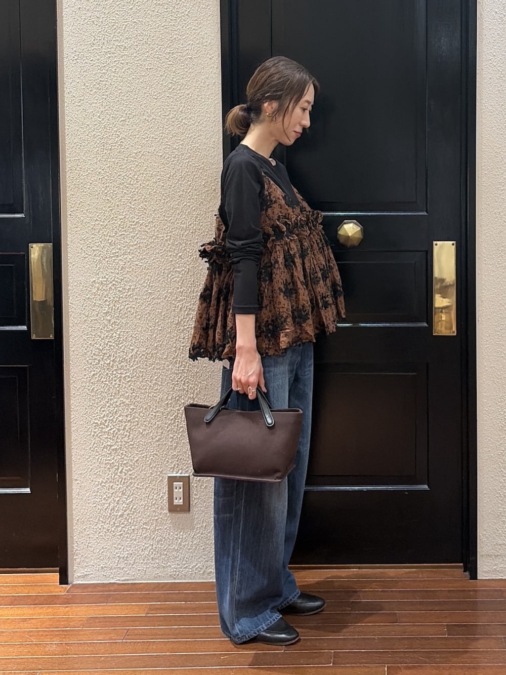 ブラウン系のキャミソール、ブルー系のデニムパンツ、ブラック系のTシャツ/カットソーを着用したレディースの秋コーディネートの2枚目の写真