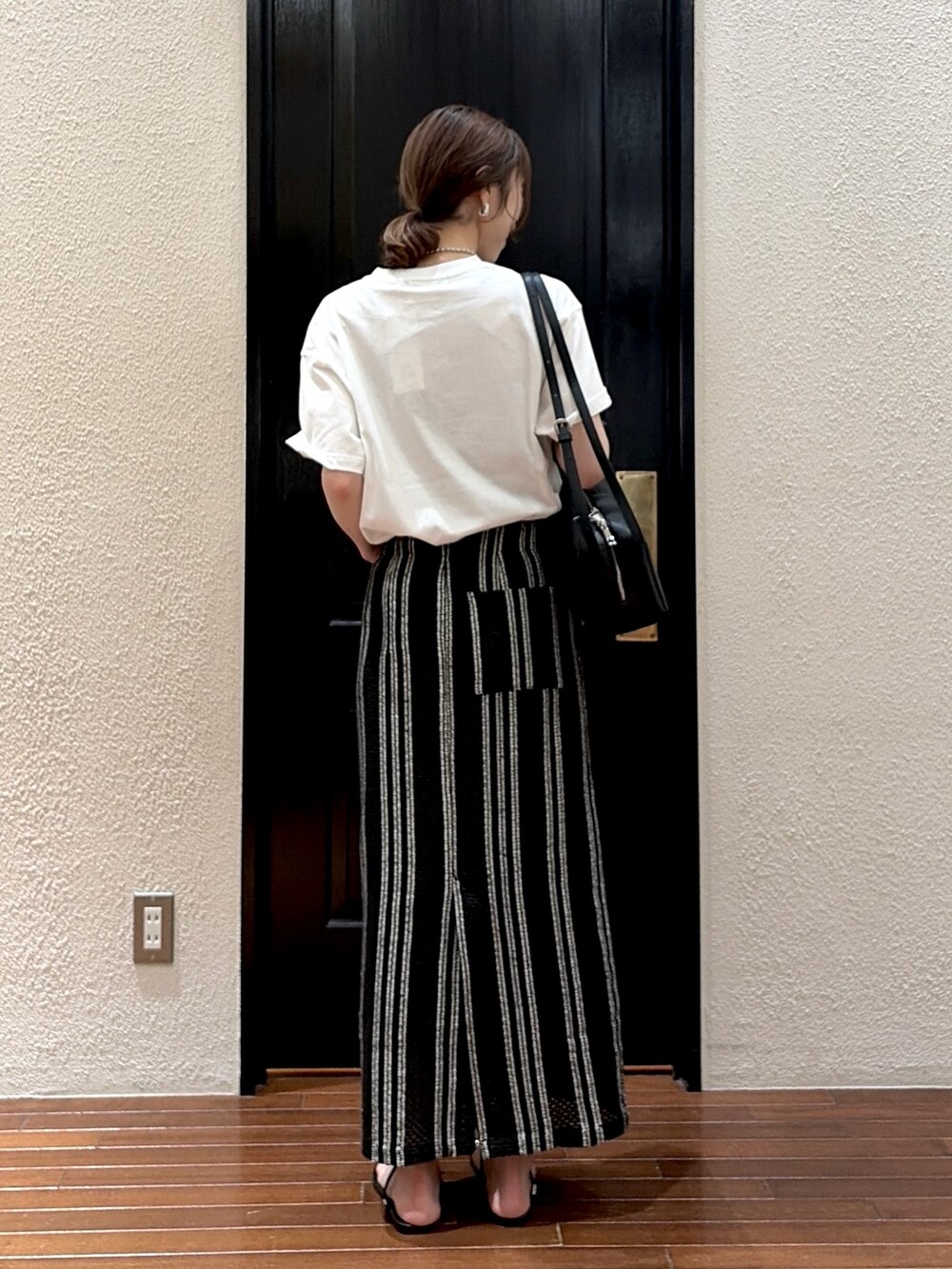 ブラック系のスカート、ホワイト系のTシャツ/カットソー、ブラック系のサンダルを着用したレディースの夏コーディネートの3枚目の写真