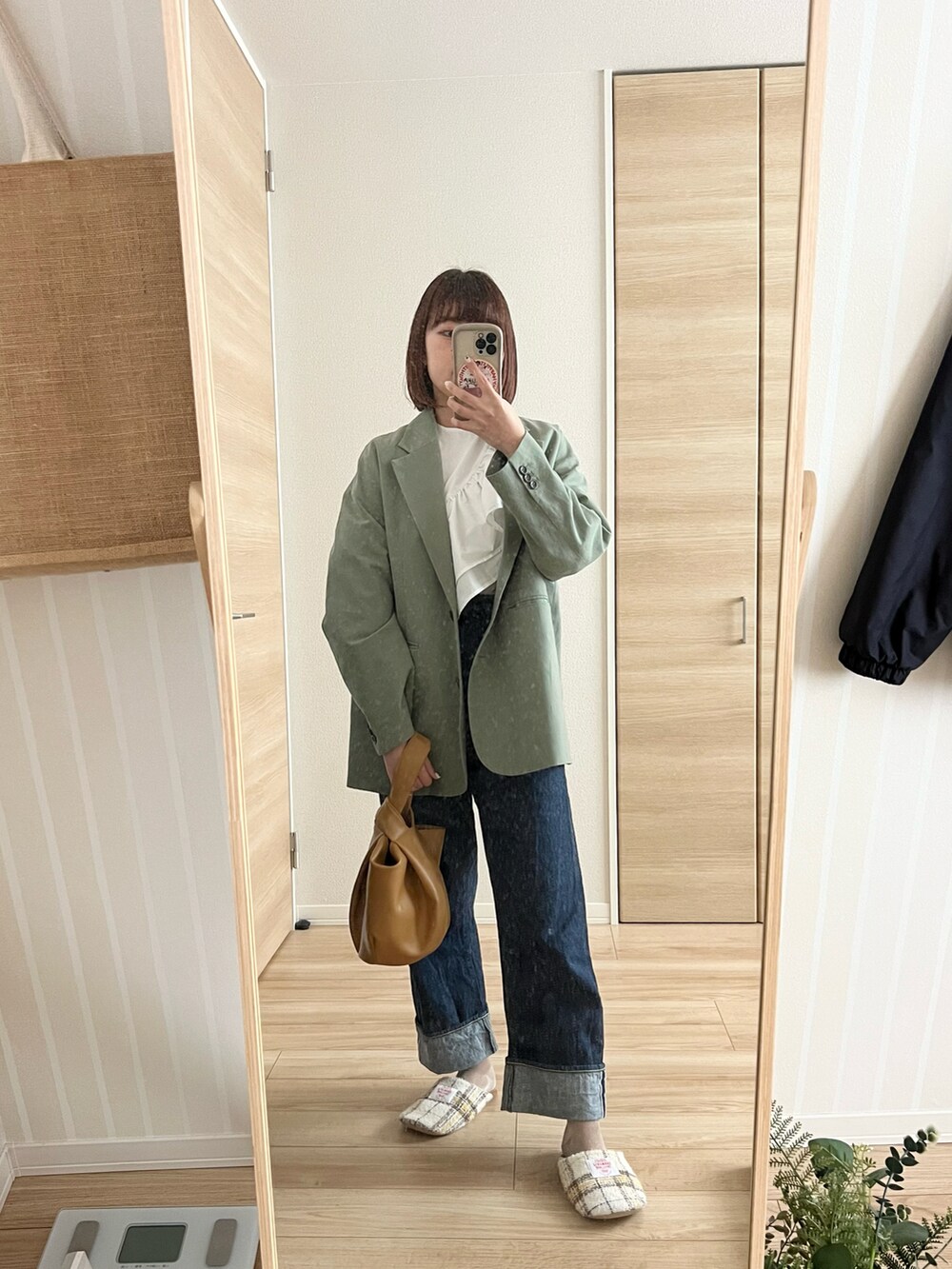 ブルー系のデニムパンツ、イエロー系のハンドバッグ、グリーン系のテーラードジャケットを着用したレディースの春コーディネートの3枚目の写真