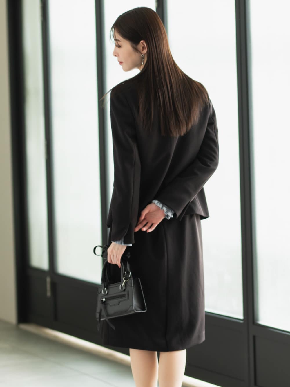 ブルー系のシャツ/ブラウス、ブラック系のスーツジャケット、ブラック系のスーツスカートを着用したレディースの冬コーディネートの3枚目の写真