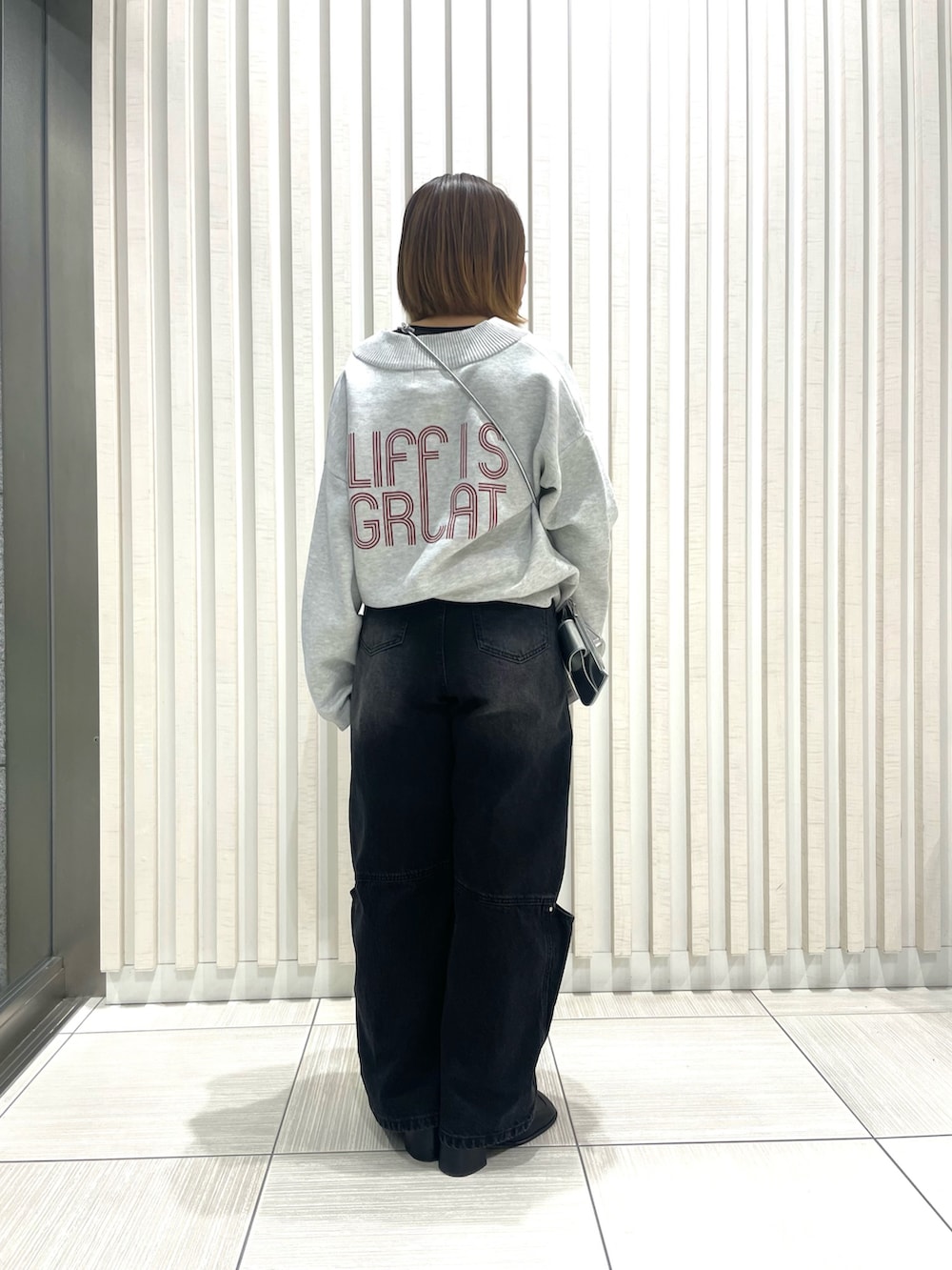 グレー系のニット/セーター、ホワイト系のブルゾンを着用したレディースの冬コーディネートの2枚目の写真