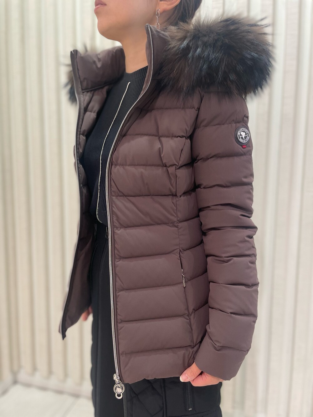 ブラウン系のダウンジャケット/コート、ブラック系のブーツを着用したレディースの秋コーディネートの2枚目の写真