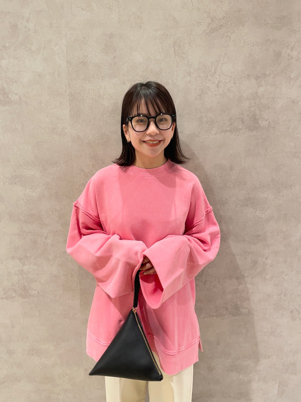 ピンク系のスウェット、ホワイト系のその他パンツ、ブラック系のポーチを着用したレディースの冬コーディネートの2枚目の写真