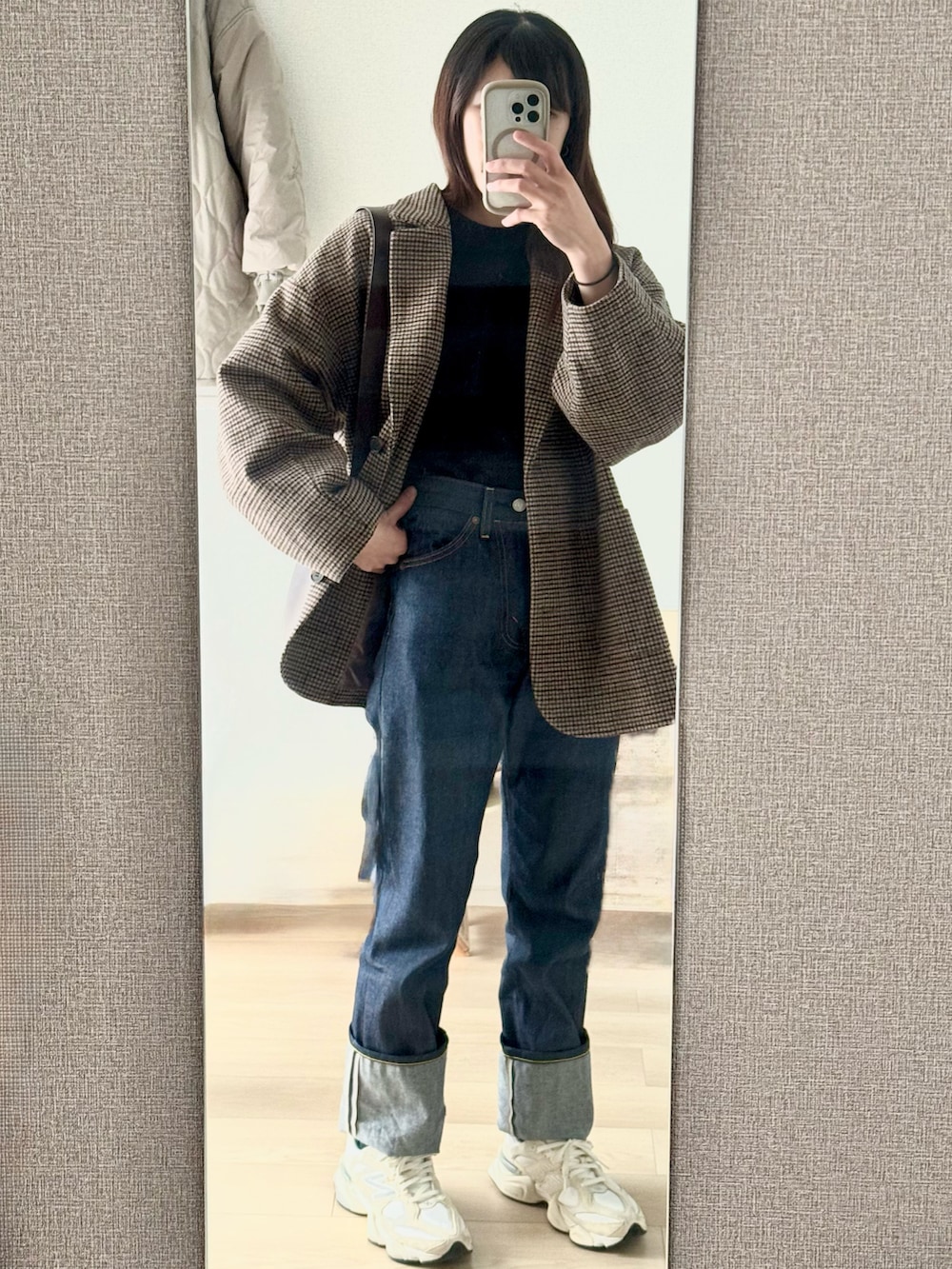 ブルー系のデニムパンツ、ブラック系のニット/セーター、ブラウン系のテーラードジャケットを着用したレディースの秋コーディネートの2枚目の写真