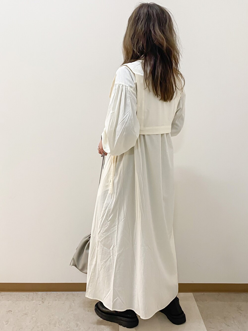 ホワイト系のワンピース、ベージュ系のハンドバッグ、ブラック系のブーツを着用したレディースの冬コーディネートの3枚目の写真