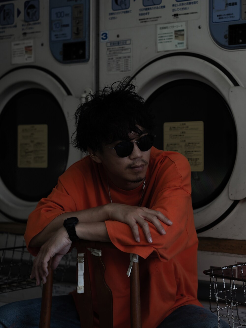 オレンジ系のトップス、ブルー系のデニムパンツ、ホワイト系のスニーカーを着用したメンズの夏コーディネートの3枚目の写真