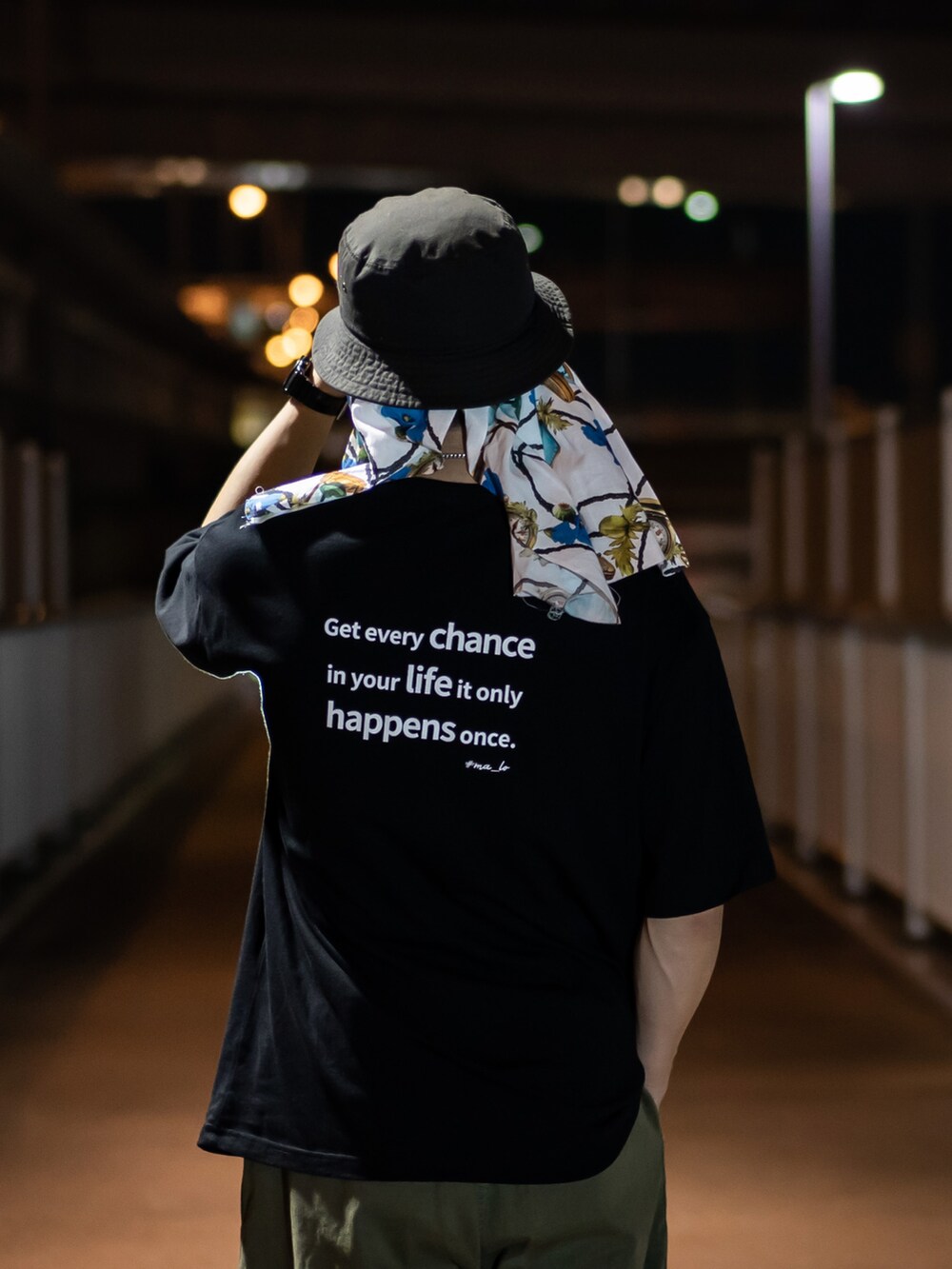 グリーン系のパンツ、ブラック系のハットを着用したメンズの夏コーディネートの2枚目の写真