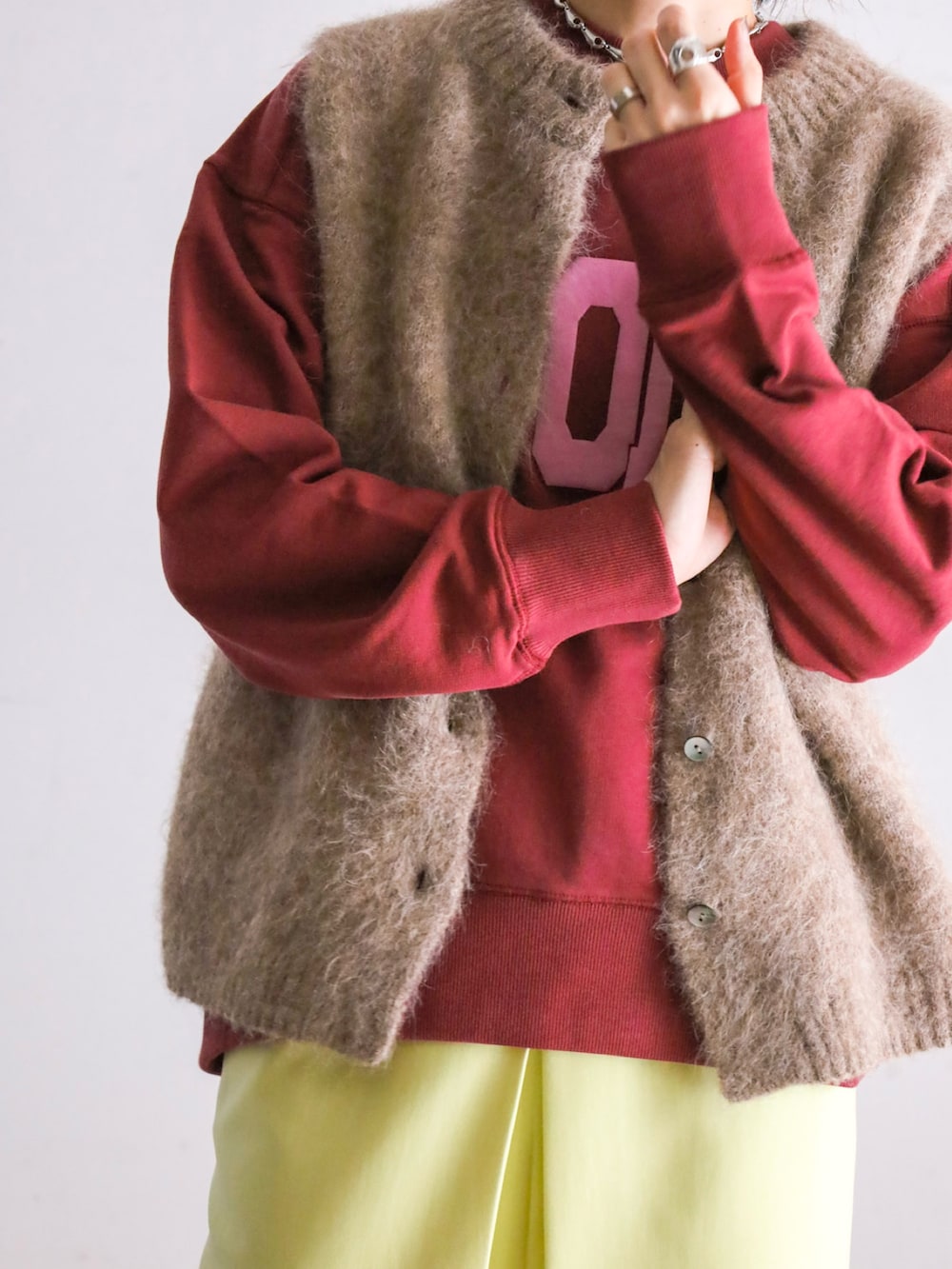 ブラウン系のベスト、レッド系のスウェット、イエロー系のスカートを着用したレディースの冬コーディネートの2枚目の写真