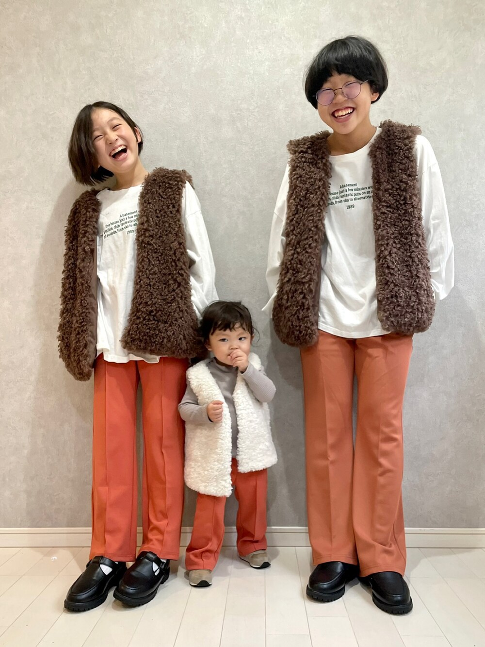 ホワイト系のTシャツ/カットソー、ブラウン系のベスト、オレンジ系のスラックスを着用したキッズの秋コーディネートの2枚目の写真