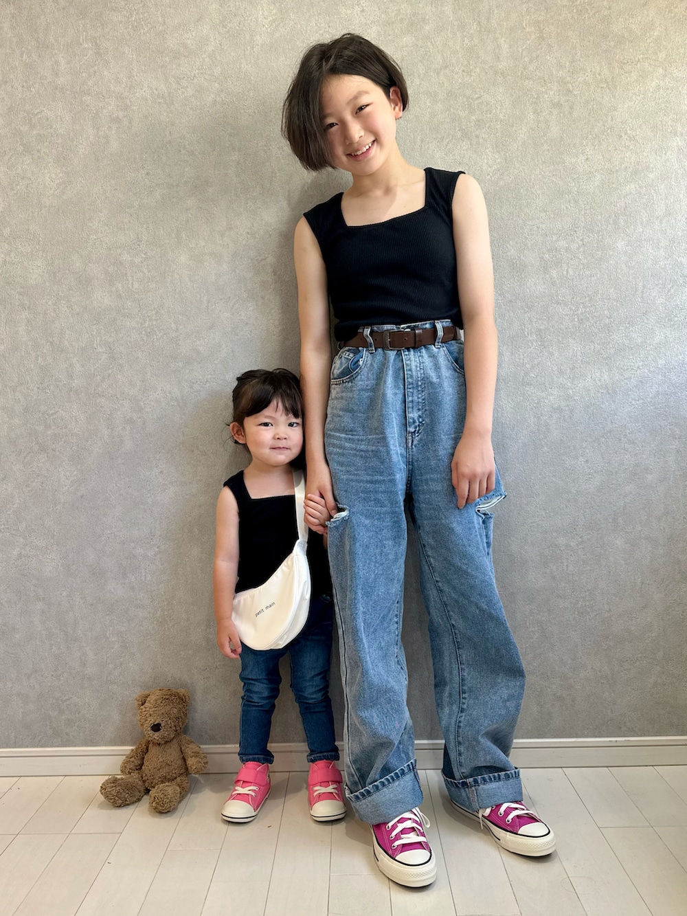 ブラック系のタンクトップ、ブルー系のデニムパンツ、ホワイト系のバックパック/リュックを着用したキッズの夏コーディネートの2枚目の写真