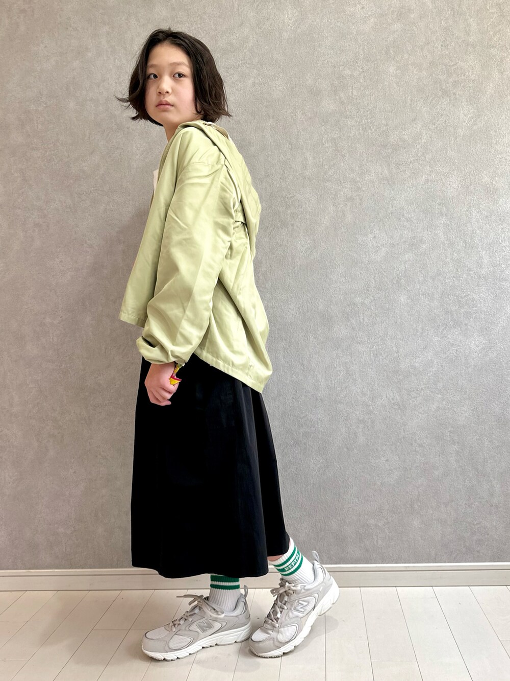 グリーン系のマウンテンパーカー、ホワイト系のTシャツ/カットソー、ブラック系のスカートを着用したキッズの春コーディネートの3枚目の写真