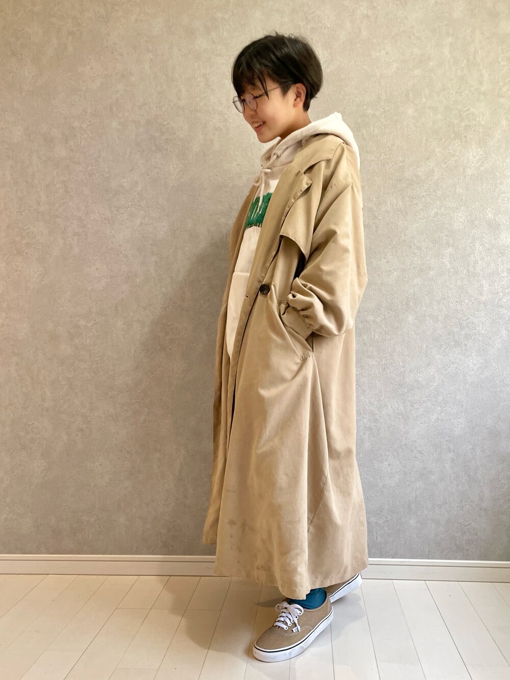 ベージュ系のトレンチコート、ホワイト系のパーカー、ブラック系のスカートを着用したキッズの冬コーディネートの3枚目の写真