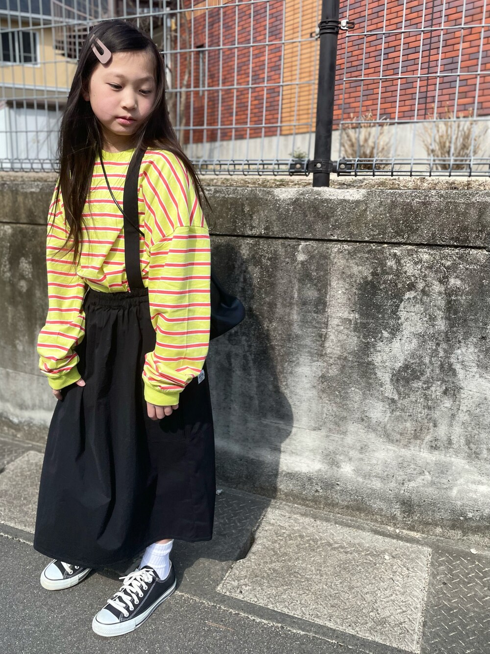 グリーン系のTシャツ/カットソー、ブラック系のスカート、ブラック系のスニーカーを着用したキッズの春コーディネートの2枚目の写真