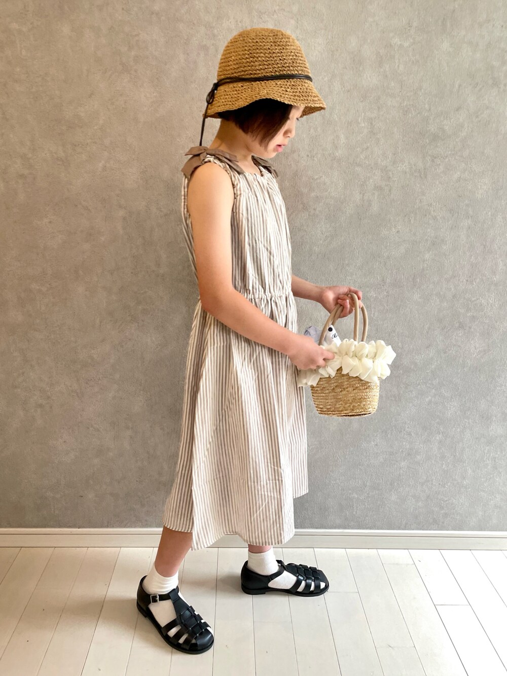 ベージュ系のワンピース、ブラック系のサンダル、ベージュ系のハットを着用したキッズの夏コーディネートの3枚目の写真