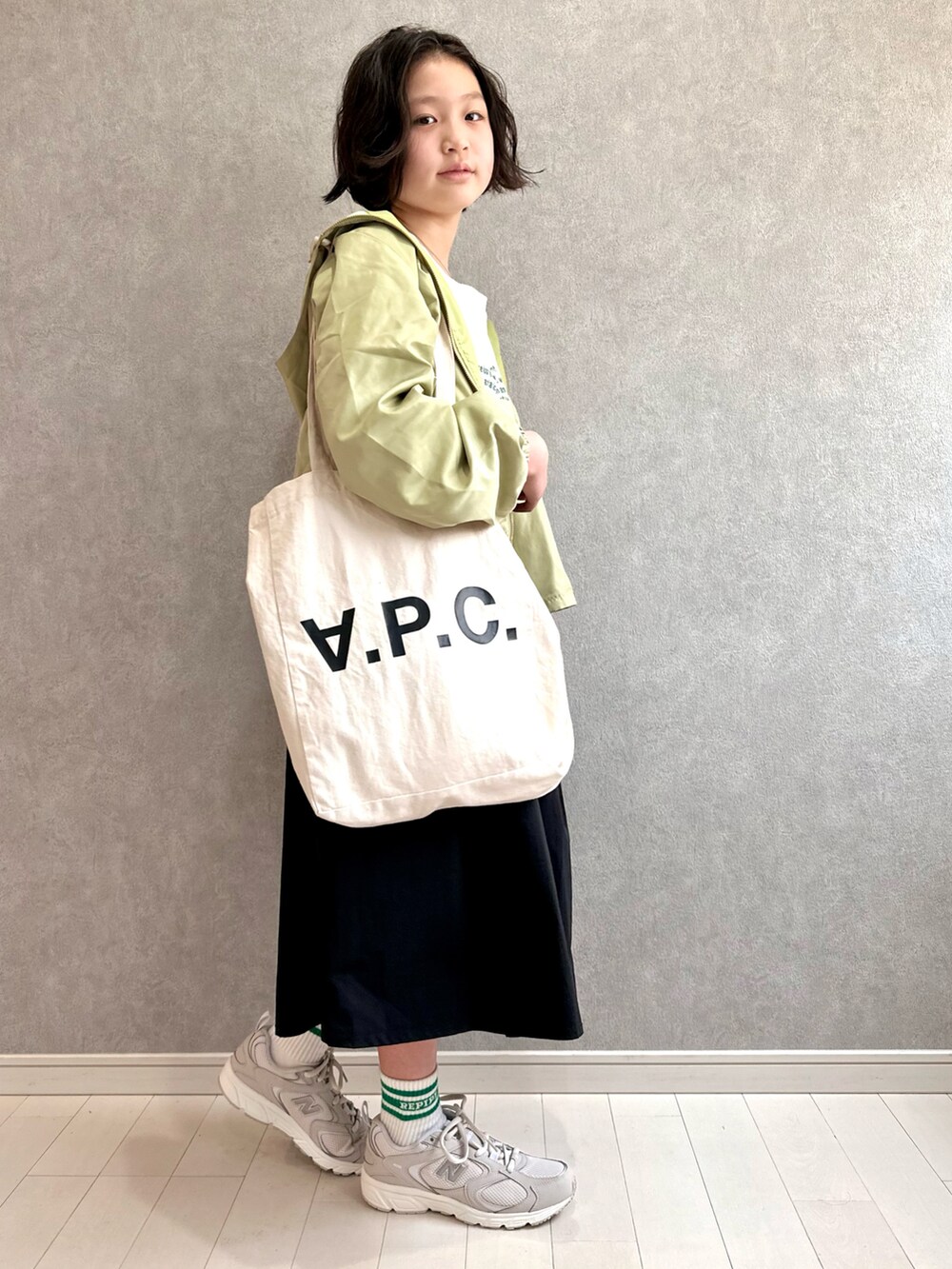 グリーン系のマウンテンパーカー、ホワイト系のTシャツ/カットソー、ブラック系のスカートを着用したキッズの春コーディネートの4枚目の写真