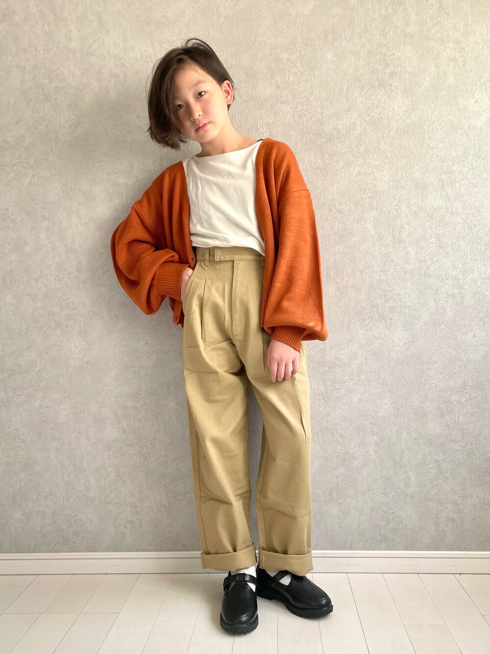 ホワイト系のTシャツ/カットソー、オレンジ系のカーディガン/ボレロ、ベージュ系のデニムパンツを着用したキッズの秋コーディネートの3枚目の写真