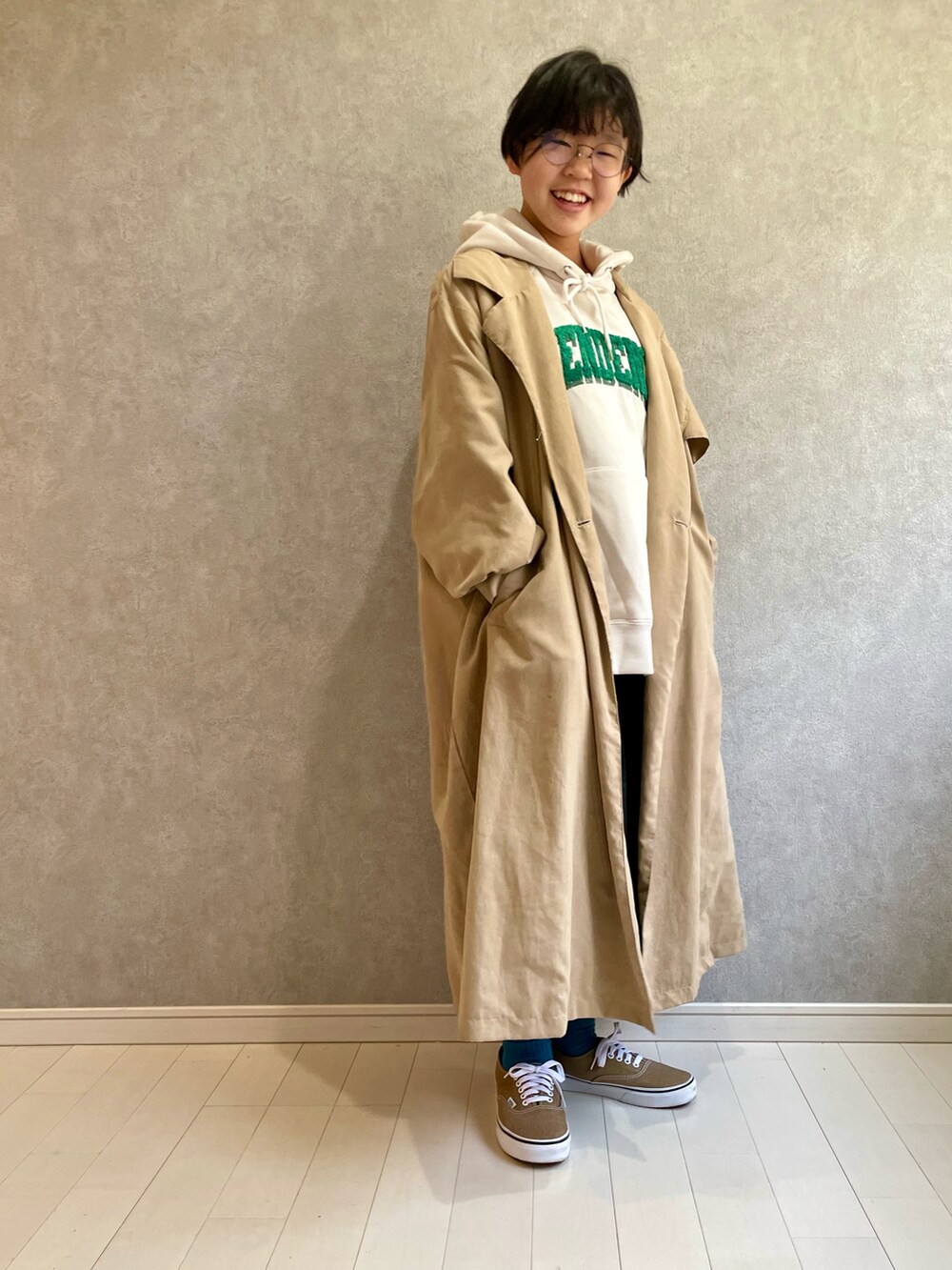 ベージュ系のトレンチコート、ホワイト系のパーカー、ブラック系のスカートを着用したキッズの冬コーディネートの2枚目の写真