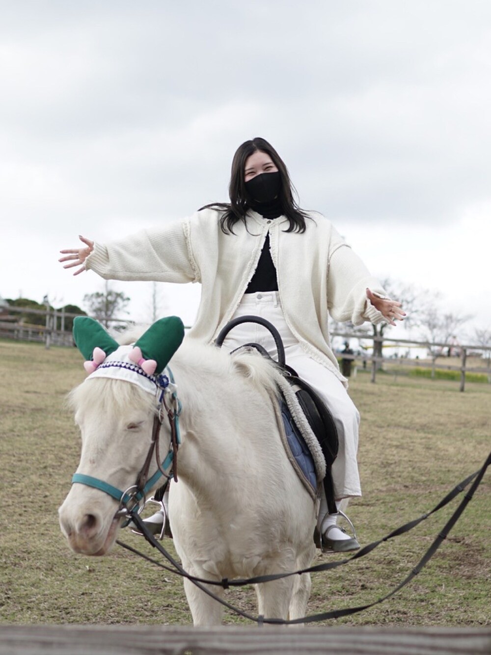 ホワイト系のデニムパンツ、グリーン系のパンプス、ホワイト系のニット/セーターを着用したレディースの冬コーディネートの2枚目の写真
