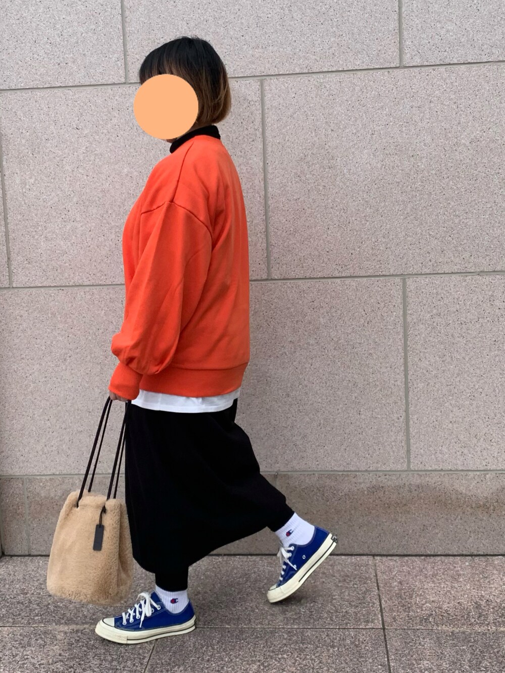 オレンジ系のスウェット、ブルー系のスニーカー、ブラック系のワンピースを着用したレディースの冬コーディネートの2枚目の写真