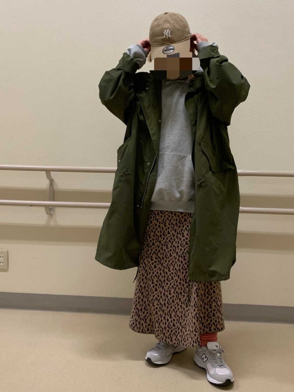 グリーン系のモッズコート、ベージュ系のスカート、グレー系のパーカーを着用したレディースの冬コーディネートの2枚目の写真