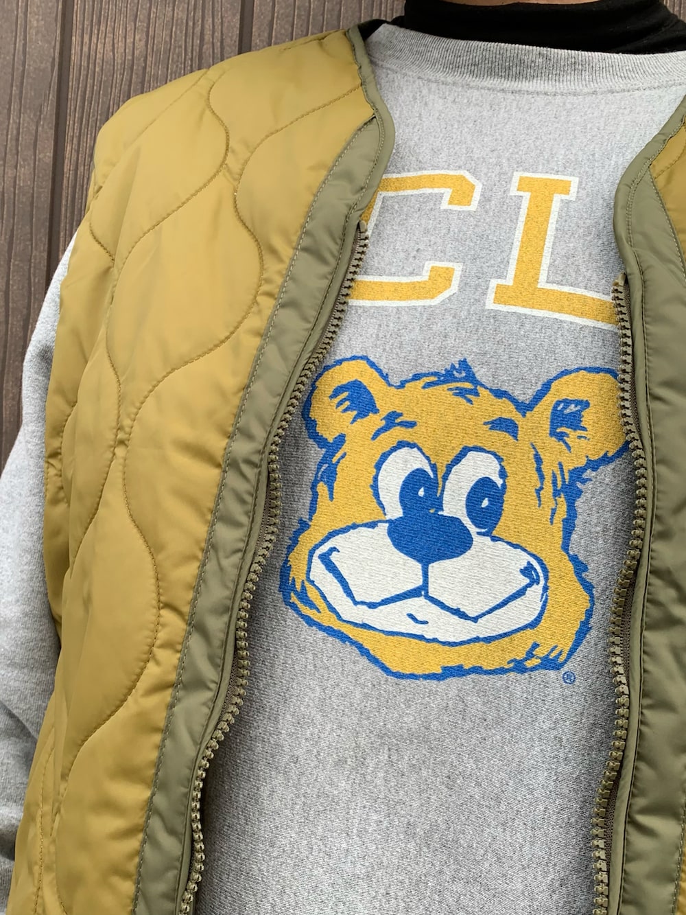 ブラック系のスニーカー、グリーン系のダウンベスト、グレー系のスウェットを着用したレディースの冬コーディネートの2枚目の写真