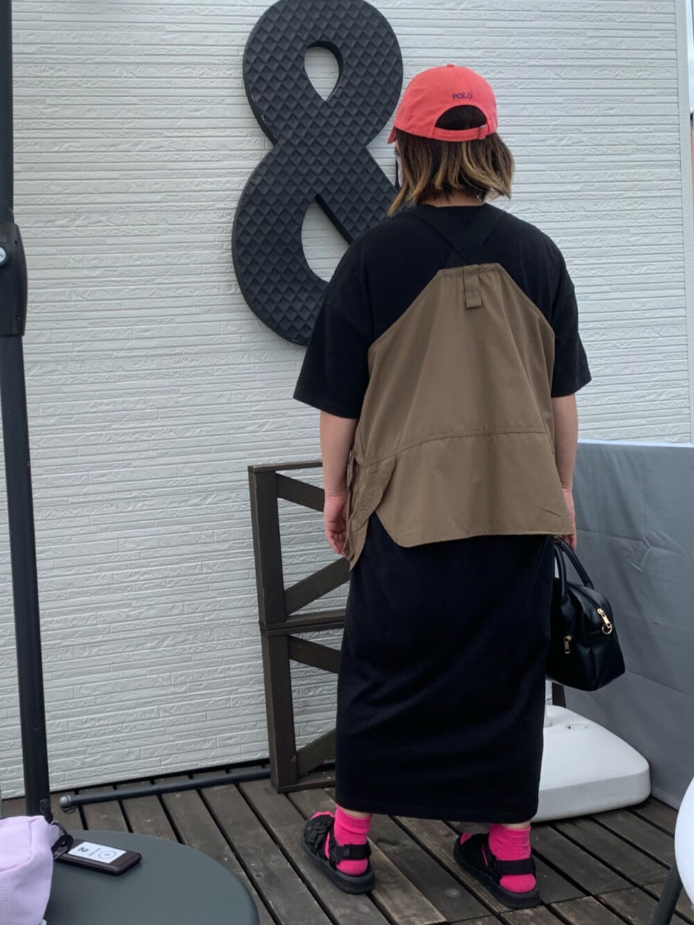 ブラック系のサンダル、ブラック系のワンピース、ピンク系のキャップを着用したレディースの夏コーディネートの2枚目の写真