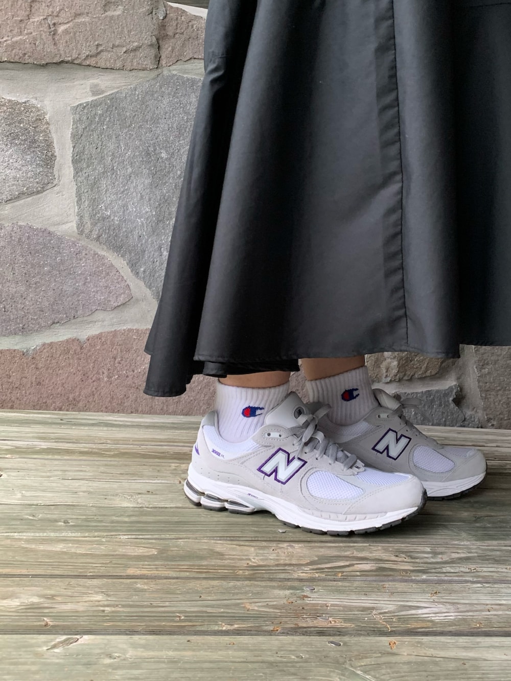 グレー系のスニーカー、ブラック系のワンピース、ブラック系のハンドバッグを着用したレディースの秋コーディネートの2枚目の写真