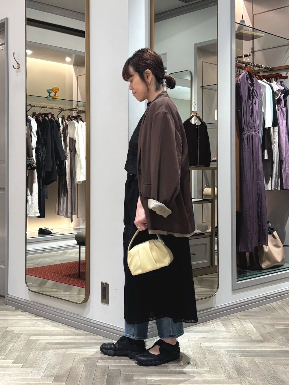 ブラック系のスニーカー、ブルー系のデニムパンツ、ブラウン系のテーラードジャケットを着用したレディースの夏コーディネートの2枚目の写真