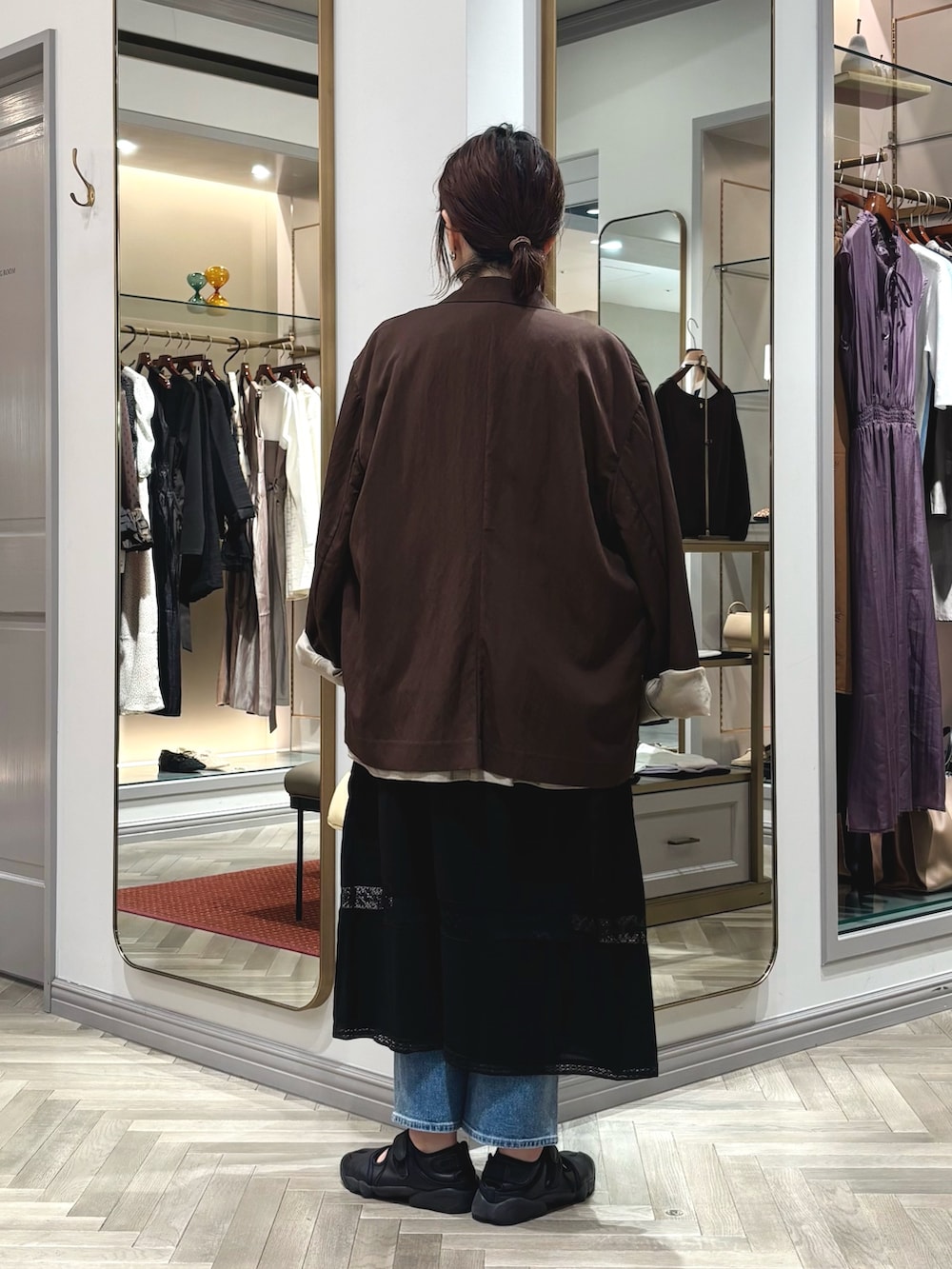 ブラック系のスニーカー、ブルー系のデニムパンツ、ブラウン系のテーラードジャケットを着用したレディースの夏コーディネートの3枚目の写真