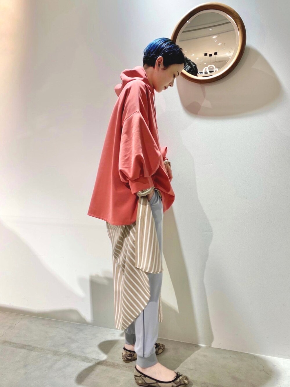 グレー系のパンツ、レッド系のパーカーを着用したレディースの春コーディネートの2枚目の写真