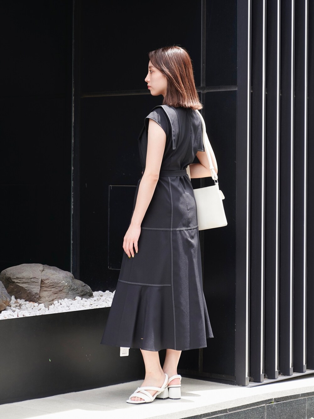 ブラック系のワンピース、ホワイト系のサンダル、ホワイト系のショルダーバッグを着用したレディースの夏コーディネートの2枚目の写真