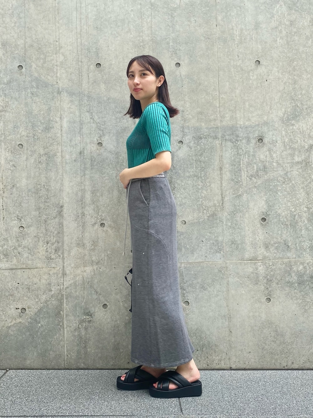 グレー系のスカート、ブルー系のニット/セーター、ブラック系のサンダルを着用したレディースの夏コーディネートの3枚目の写真