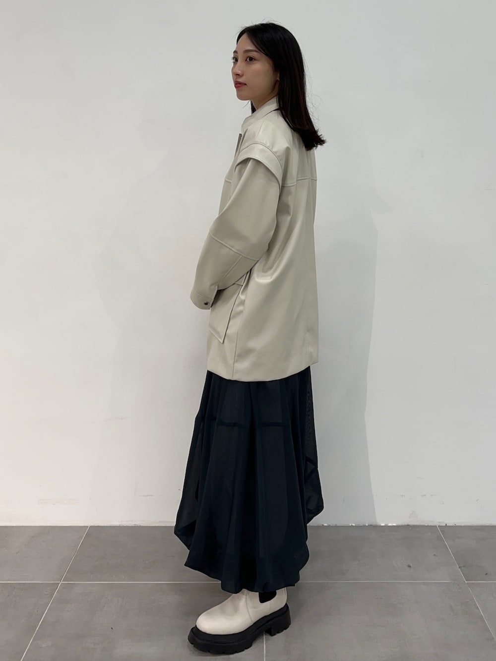 ホワイト系のブルゾン、ブルー系のスカートを着用したレディースの冬コーディネートの2枚目の写真