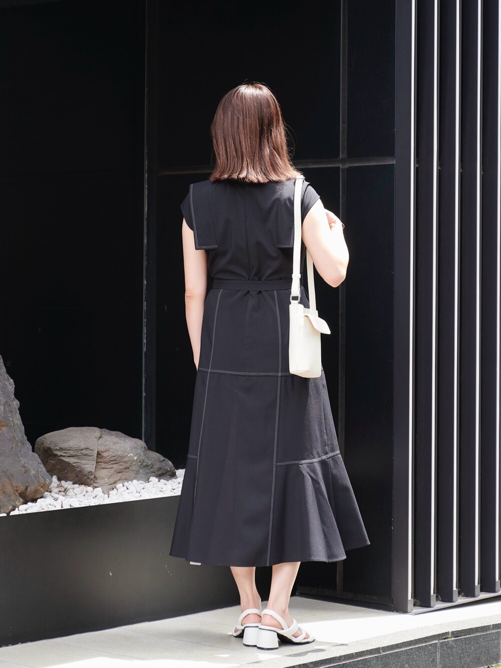 ブラック系のワンピース、ホワイト系のサンダル、ホワイト系のショルダーバッグを着用したレディースの夏コーディネートの4枚目の写真