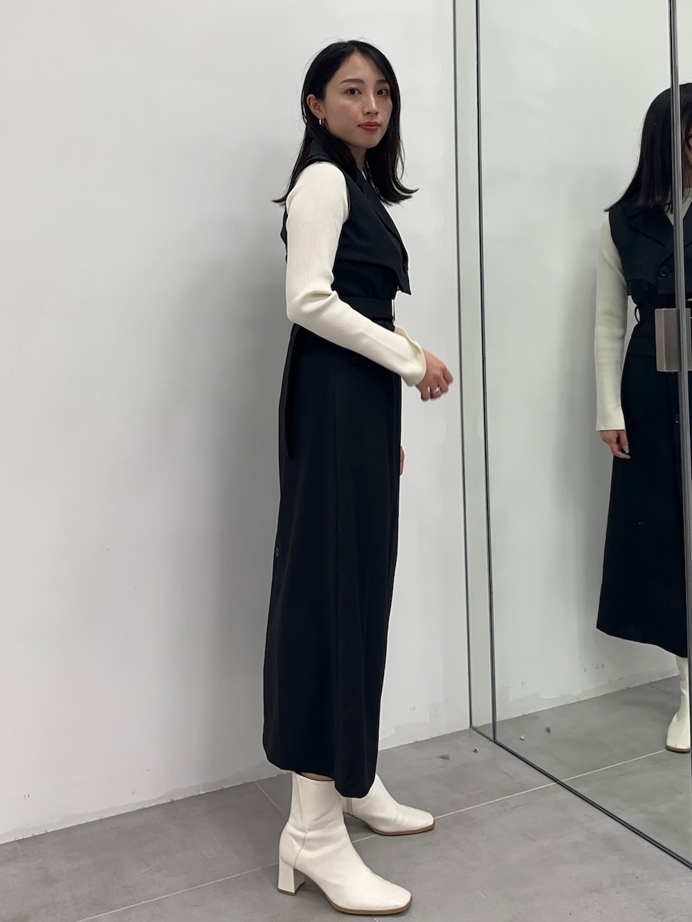 ブラック系のジャンパースカート、ベージュ系のニット/セーターを着用したレディースの冬コーディネートの2枚目の写真