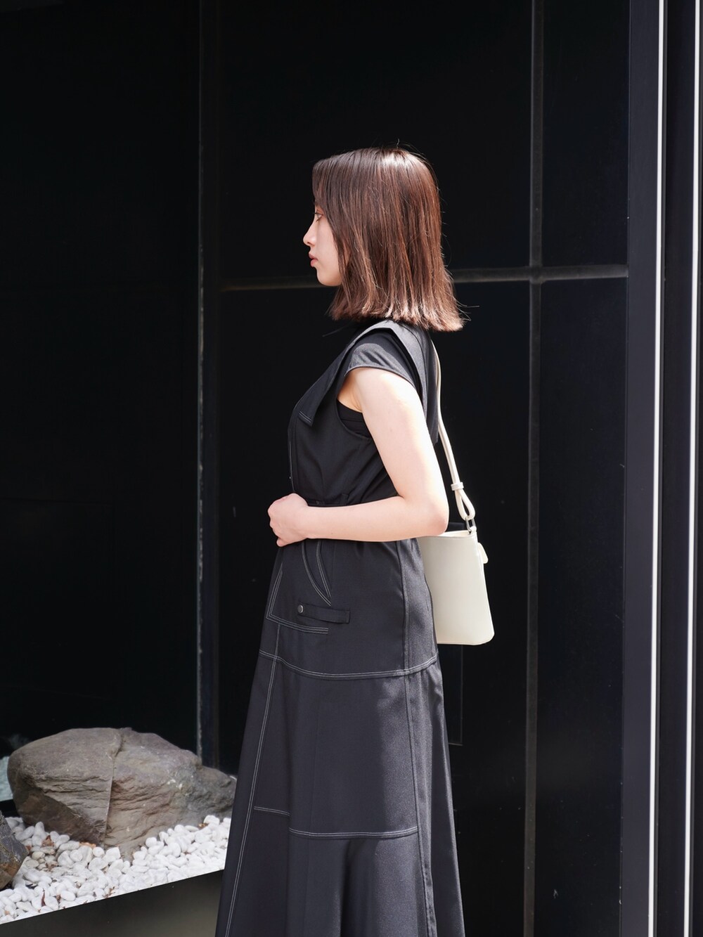 ブラック系のワンピース、ホワイト系のサンダル、ホワイト系のショルダーバッグを着用したレディースの夏コーディネートの5枚目の写真