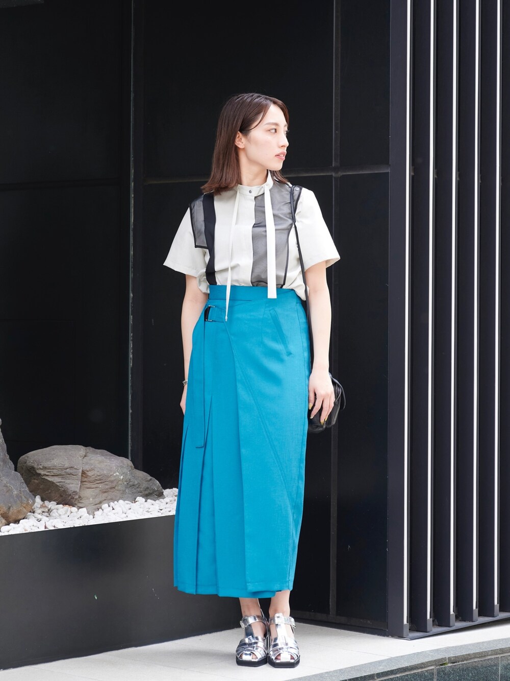 グリーン系のスカート、グレー系のシャツ/ブラウス、シルバー系のサンダルを着用したレディースの夏コーディネートの2枚目の写真