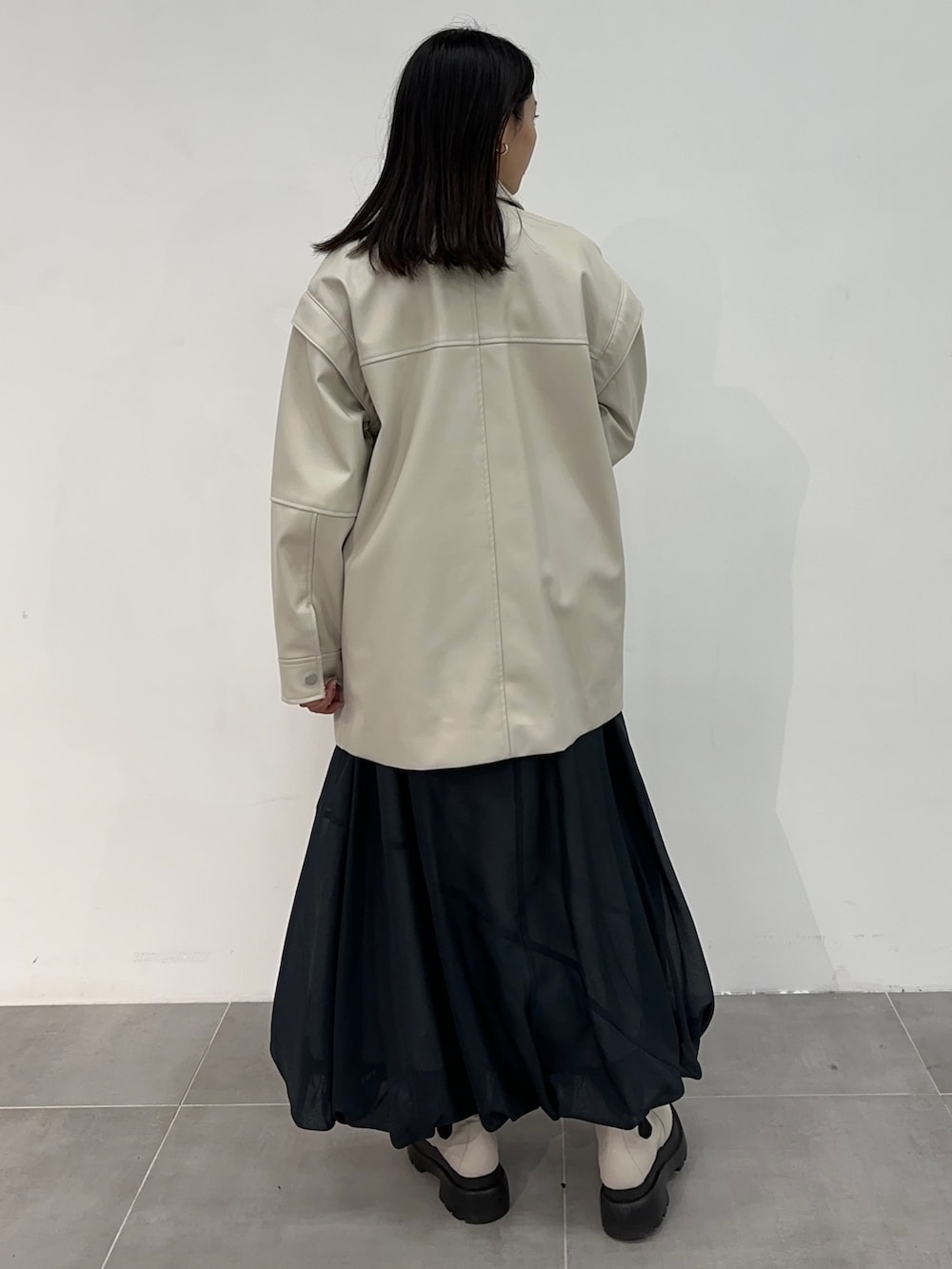 ホワイト系のブルゾン、ブルー系のスカートを着用したレディースの冬コーディネートの3枚目の写真