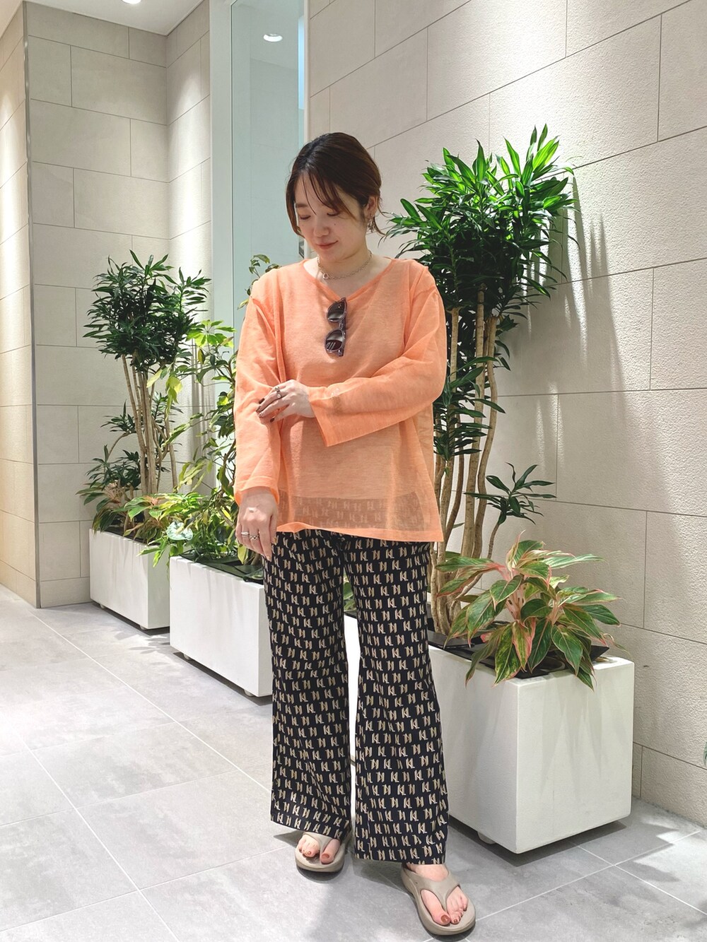 オレンジ系のニット/セーター、ブラック系のその他パンツを着用したレディースの夏コーディネートの2枚目の写真