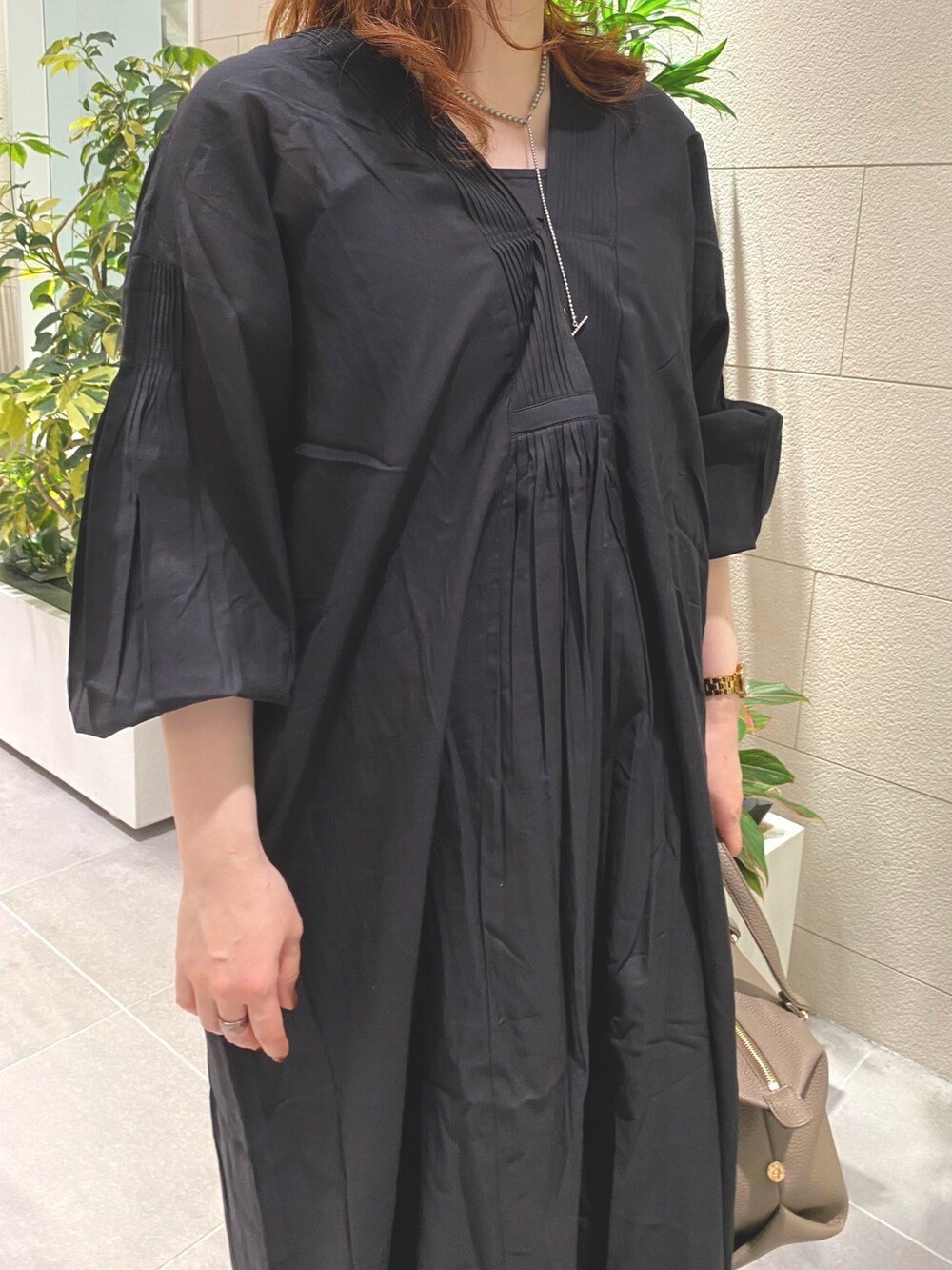 ブラック系のワンピース、ベージュ系のハンドバッグ、ゴールド系のパンプスを着用したレディースの夏コーディネートの3枚目の写真