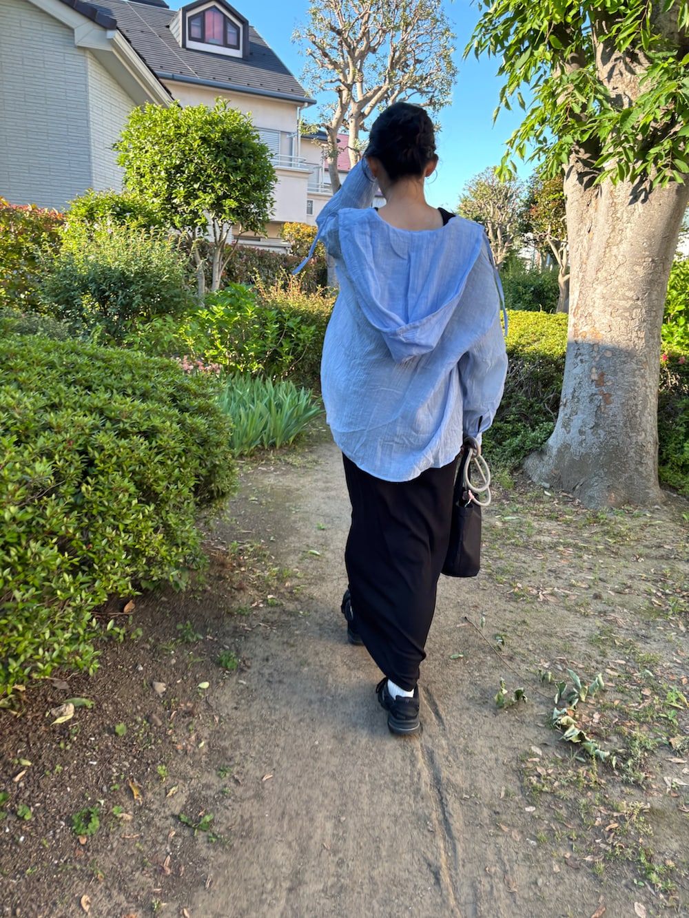 ブラック系のスニーカー、ブルー系のシャツ/ブラウス、ブラック系のワンピースを着用したレディースの春コーディネートの2枚目の写真