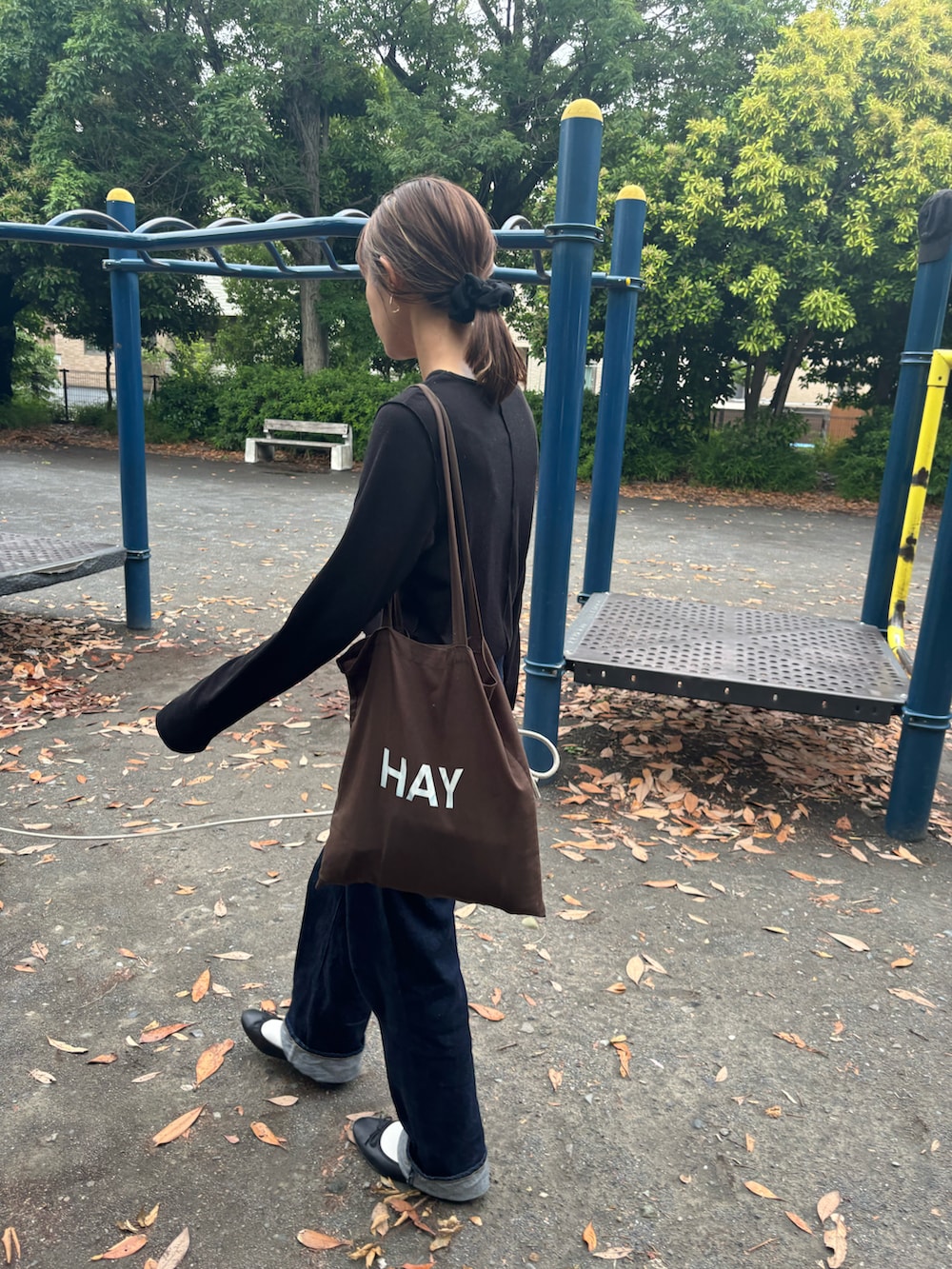 ブルー系のデニムパンツ、ブラック系のTシャツ/カットソー、ブラウン系のトートバッグを着用したレディースの春コーディネートの2枚目の写真