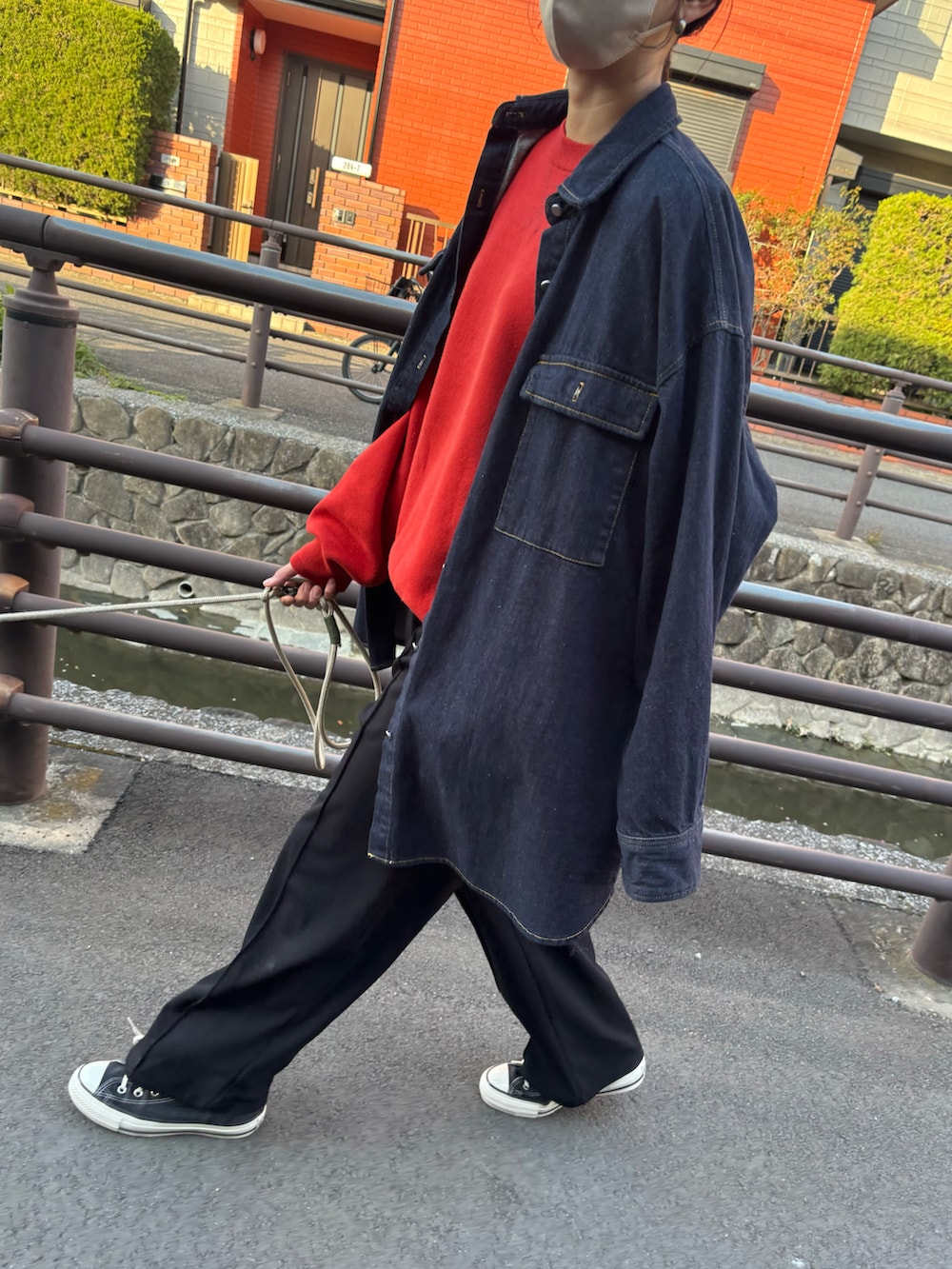 レッド系のニット/セーター、ブラック系のスニーカーを着用したレディースの春コーディネートの2枚目の写真